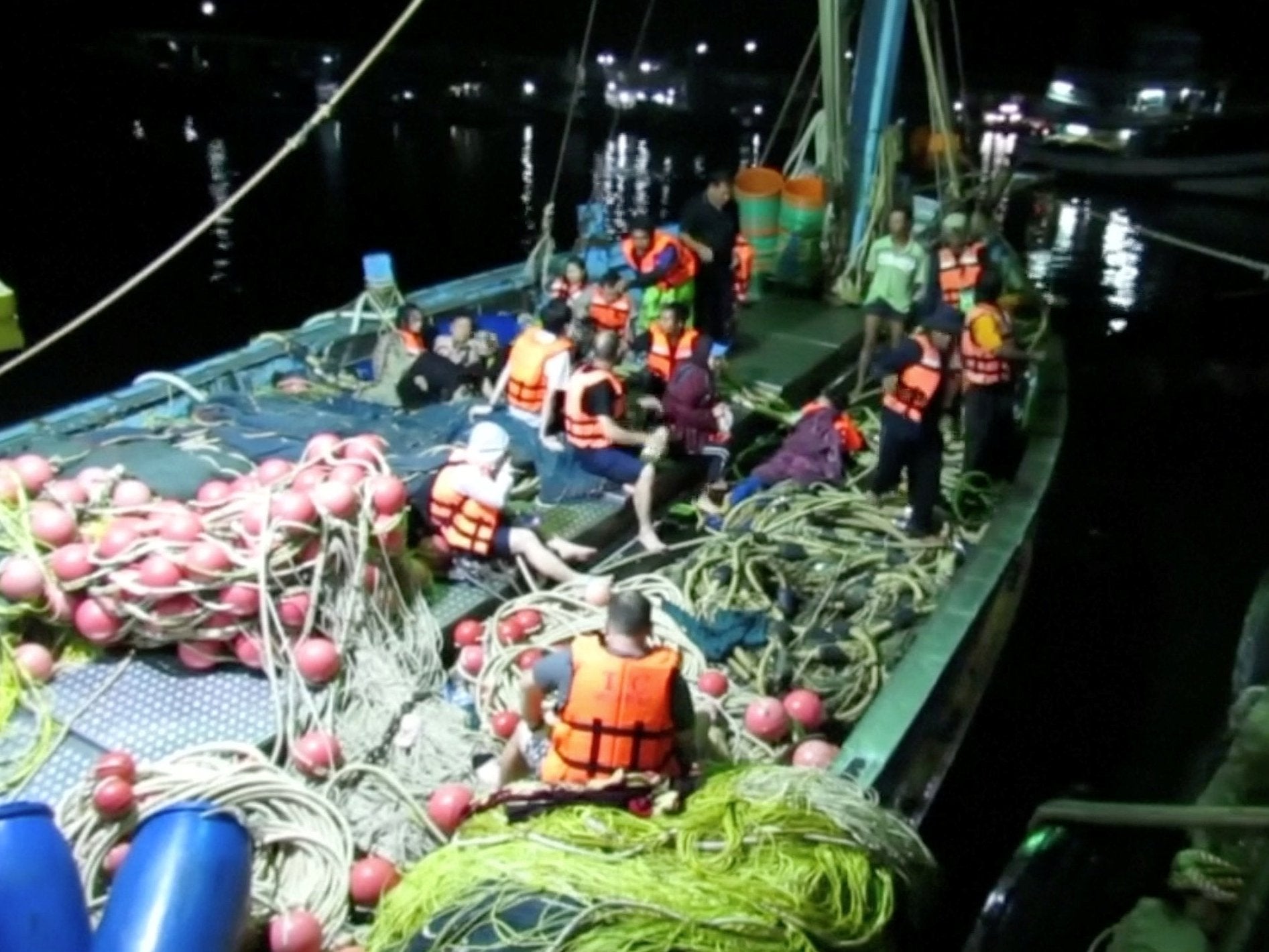 Rescued people in life jackets sit on a fishing boat after a boat they were travelling in capsized off Phuket