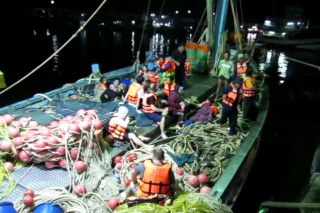Rescued people in life jackets sit on a fishing boat after a boat they were travelling in capsized off Phuket