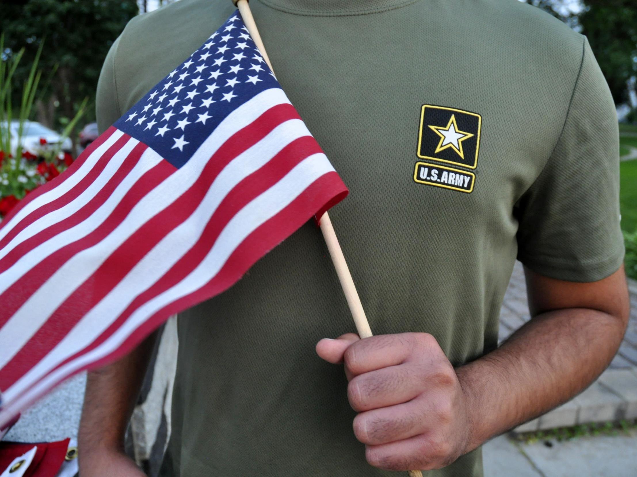 A Pakistani recruit, recently discharged by the US Army, holds an American flag