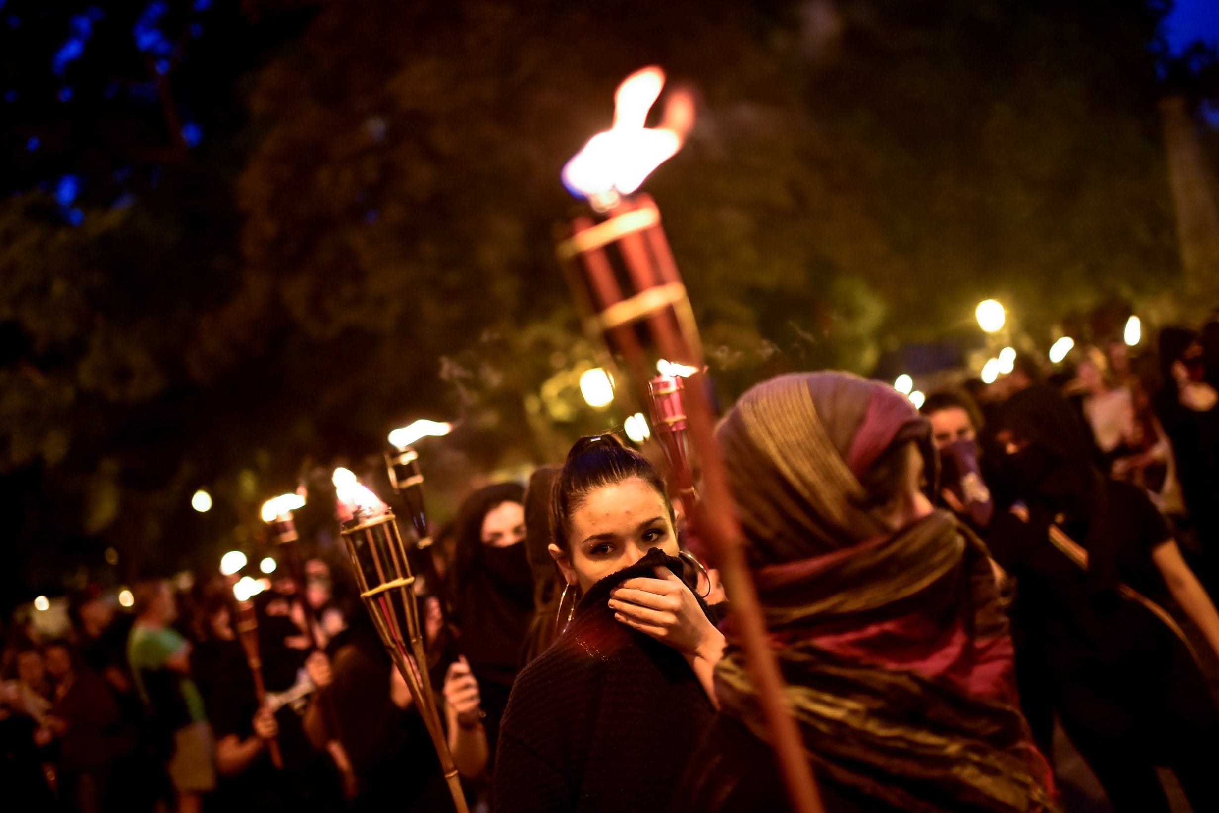 Woman activists hold candles with their faces covered, while taking part in a protest against male violence, a few days before the famous San Fermin festival, in Pamplona, northern Spain, Wednesday, July 4.