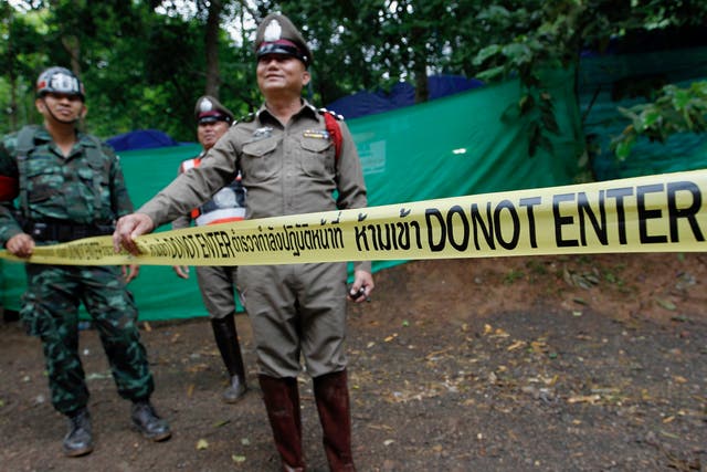 Thai police officers and military personnel stand guard outside the Tham Luang cave complex in Chiang Rai