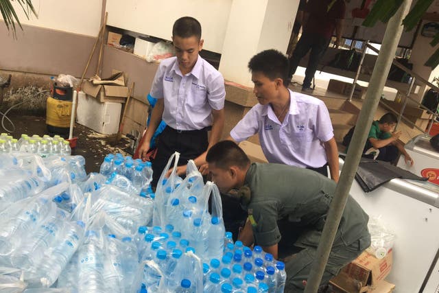 Gan, left, helps to stack water for rescue personnel at the Mae Sai cave site