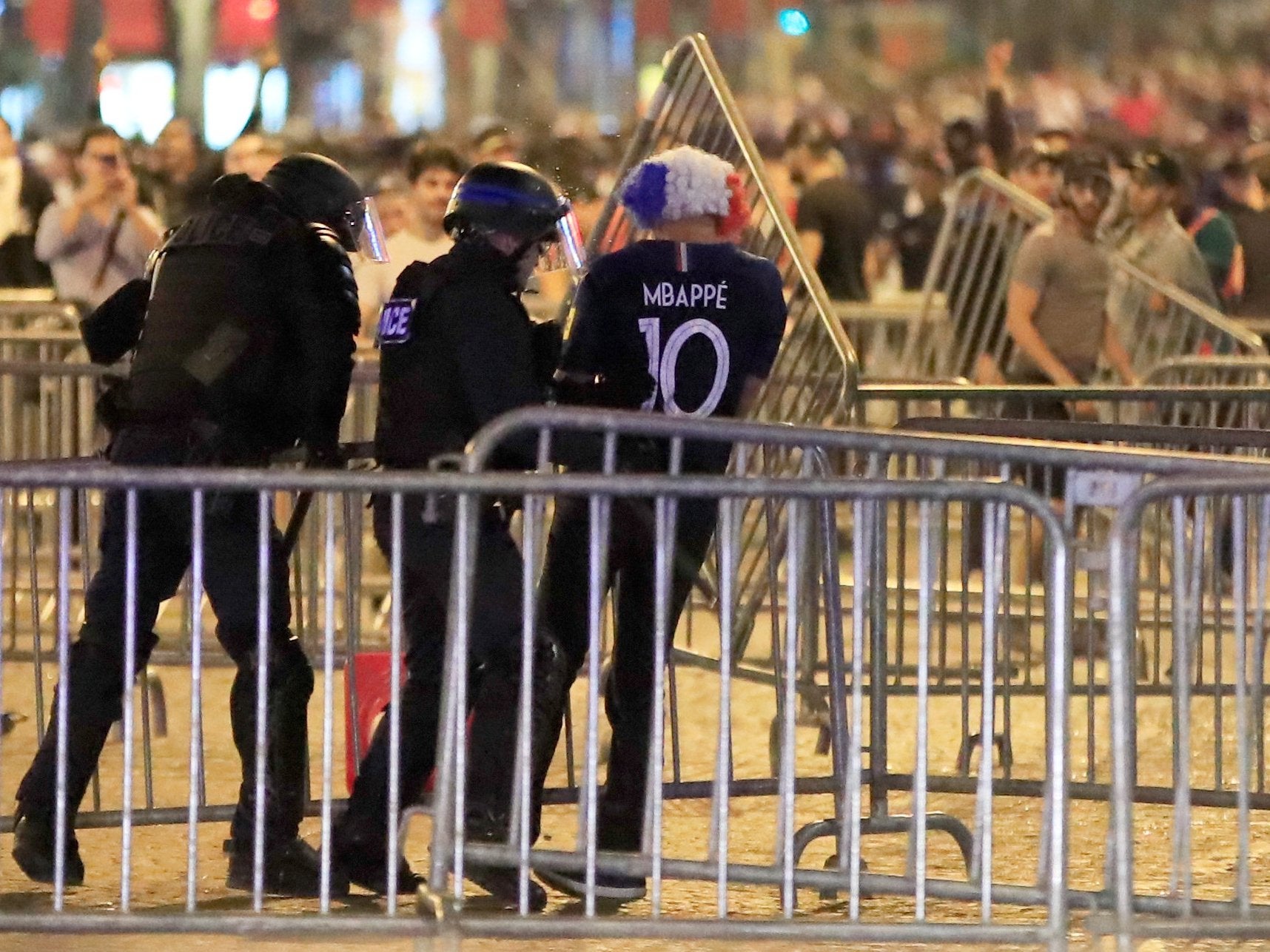 Police apprehend a France fan during clashes on the Champs-Elysees after their World Cup semi-final victory