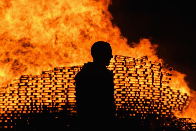 Loyalist are silhouetted as they gather in front of the bonfire on the Sandy Row area on July 12, 2017 in Belfast, Northern Ireland