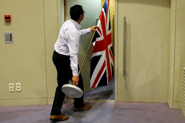 An official carries a Union Jack flag ahead of a news conference by Britain's Secretary of State for Exiting the European Union David Davis and European Union's chief Brexit negotiator Michel Barnier in Brussels