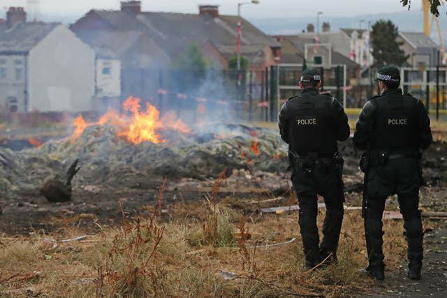 Contractors flanked by police dismantled two pyres in east Belfast on Wednesday