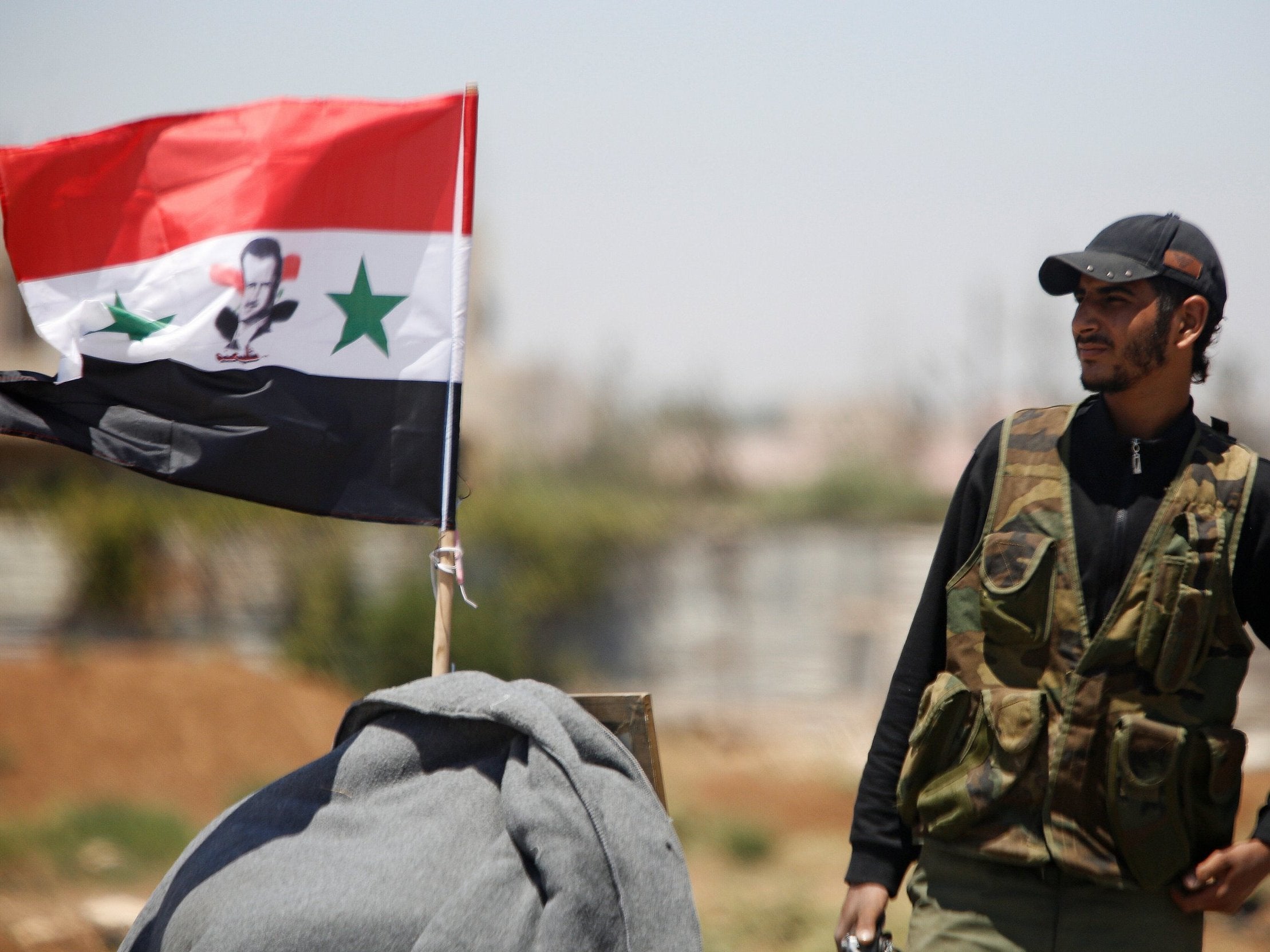 A Syrian army soldier raises the flag in Umm al-Mayazen, in the countryside of Deraa, in July