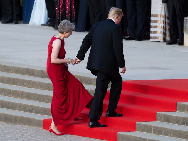 Theresa May takes the hand of Donald Trump as they walk up red-carpeted steps to enter Blenheim Palace