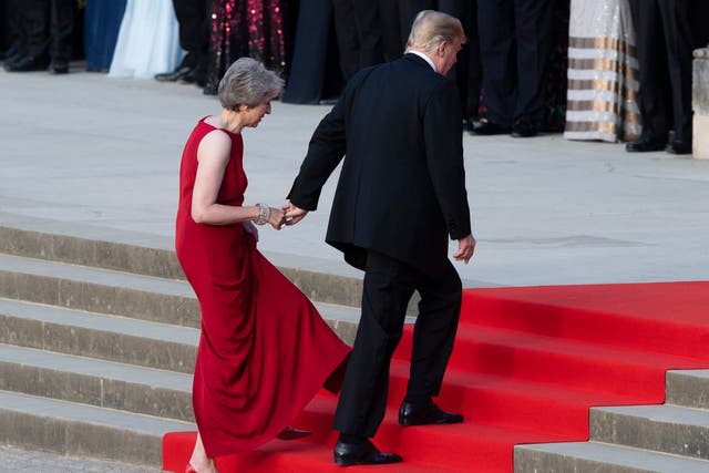 Theresa May takes the hand of Donald Trump as they walk up red-carpeted steps to enter Blenheim Palace