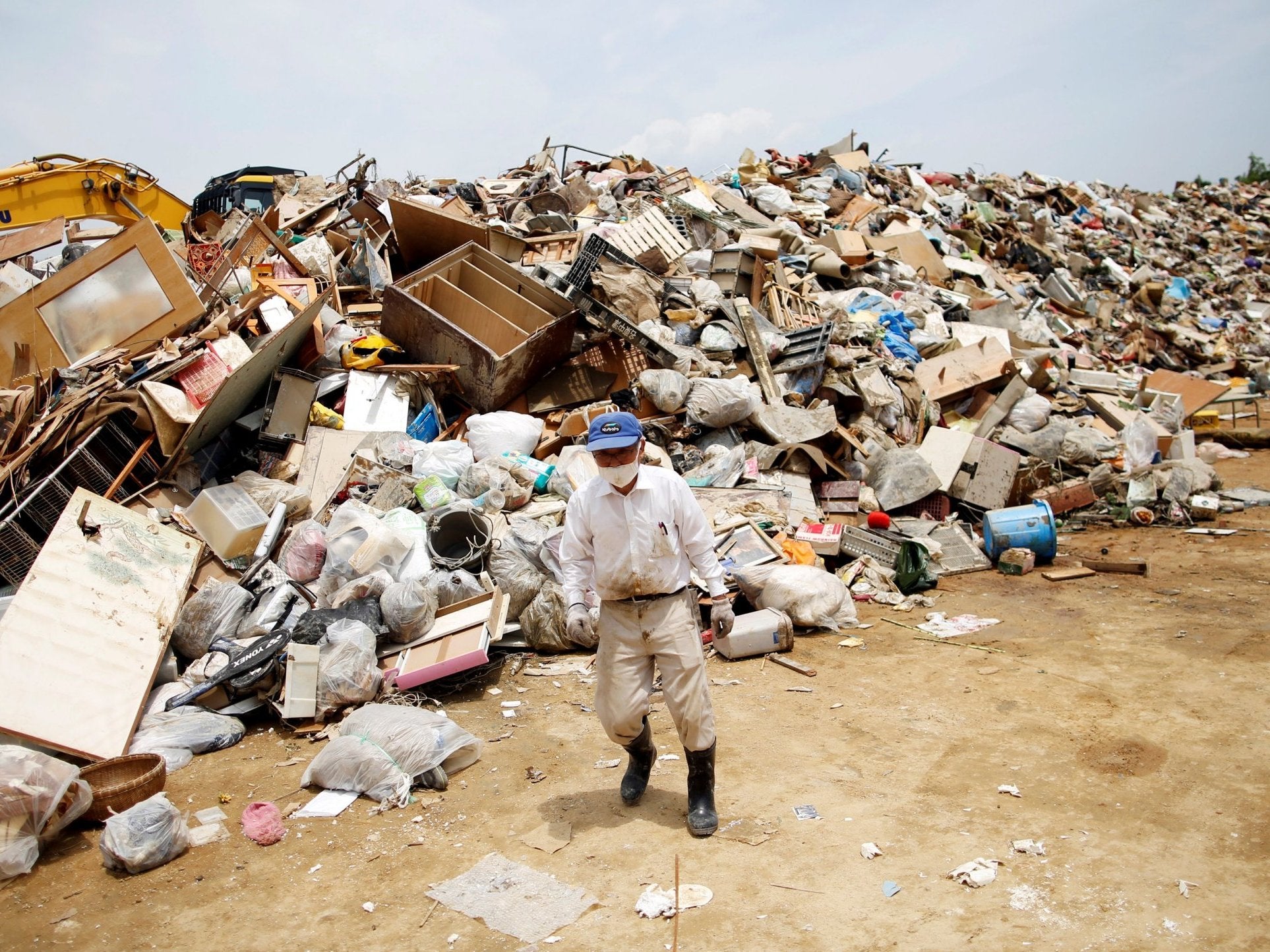 A resident piles up household waste caused by flooding in Okayama Prefecture