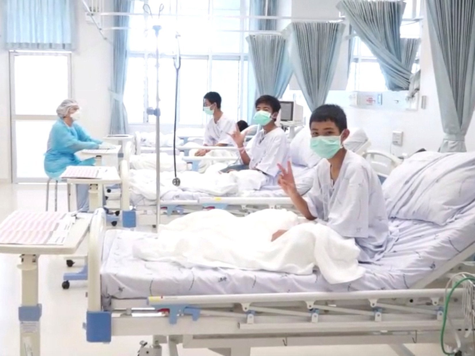 Resting in a hospital in Chiang Rai, some of the boys give victory signs (Reuters)