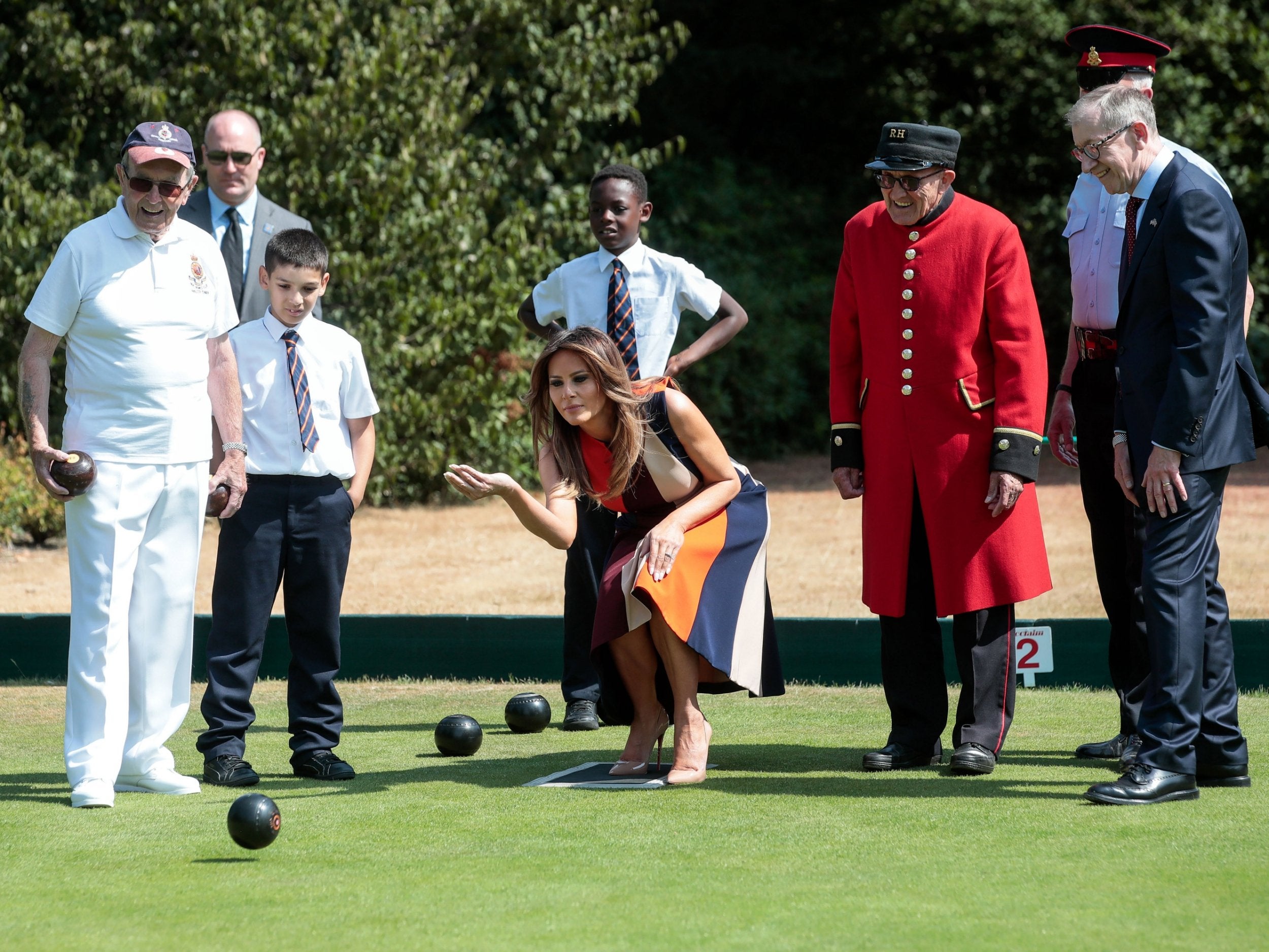 US First Lady Melania Trump (C) tries her hand at lawn bowls as Philip May (R), husband of British Prime Minister Theresa May, watches on