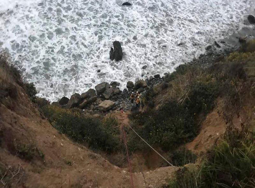 Rescuers in helmets are visible in the small bay in Big Sur, California, where a stranded woman was found by hikers