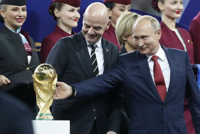 Russian President Vladimir Putin touches the World Cup trophy as Fifa President Gianni Infantino stands beside him
