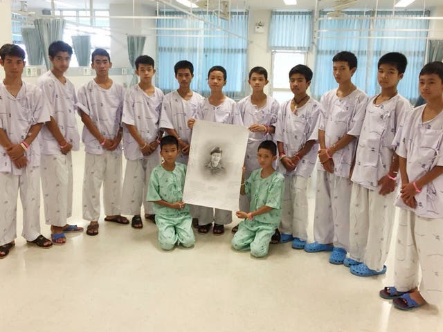 The Thai boys and their coach rescued from the cave pose with a picture of the Thai Navy Seal diver who died during the daring rescue