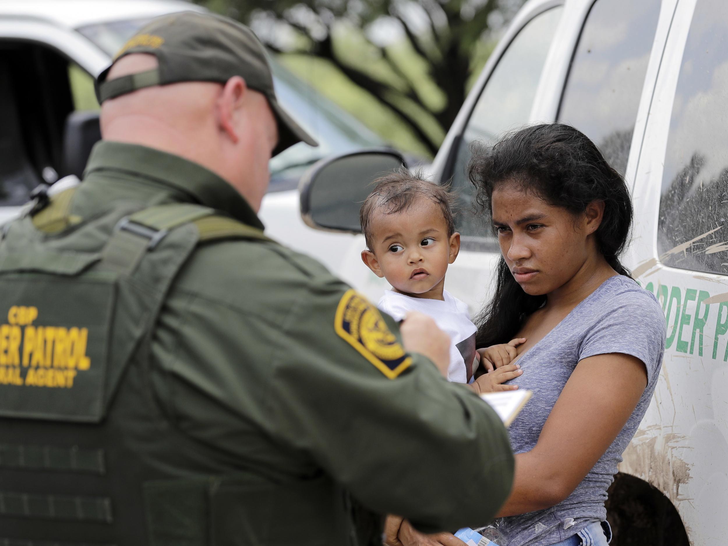 A mother migrating from Honduras holds her 1-year-old child as surrendering to U.S. Border Patrol agents after illegally crossing the border, near McAllen, Texas