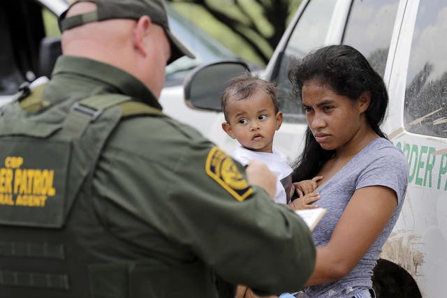 A mother migrating from Honduras holds her 1-year-old child as surrendering to U.S. Border Patrol agents after illegally crossing the border, near McAllen, Texas