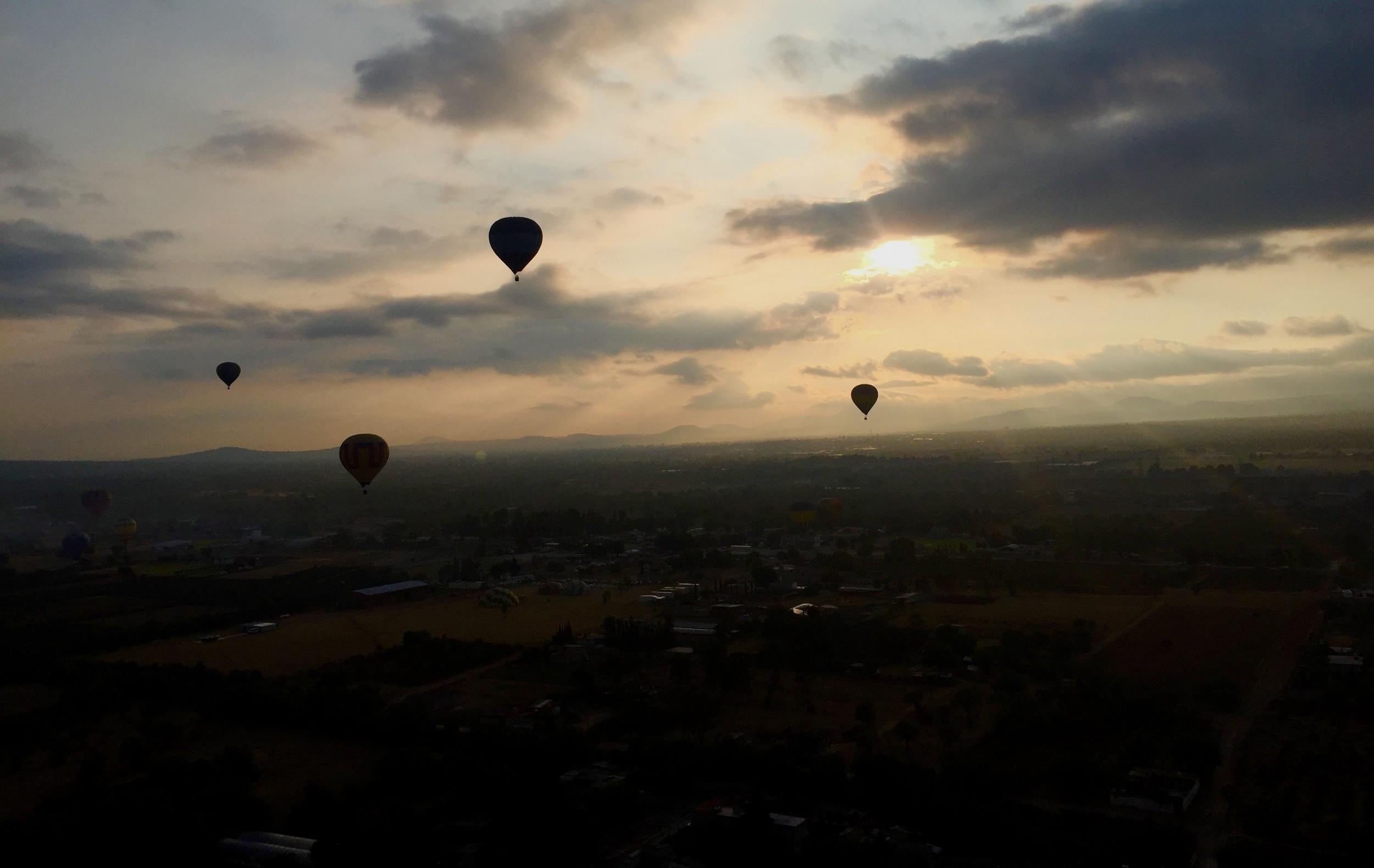 Hot air balloons float towards the city
