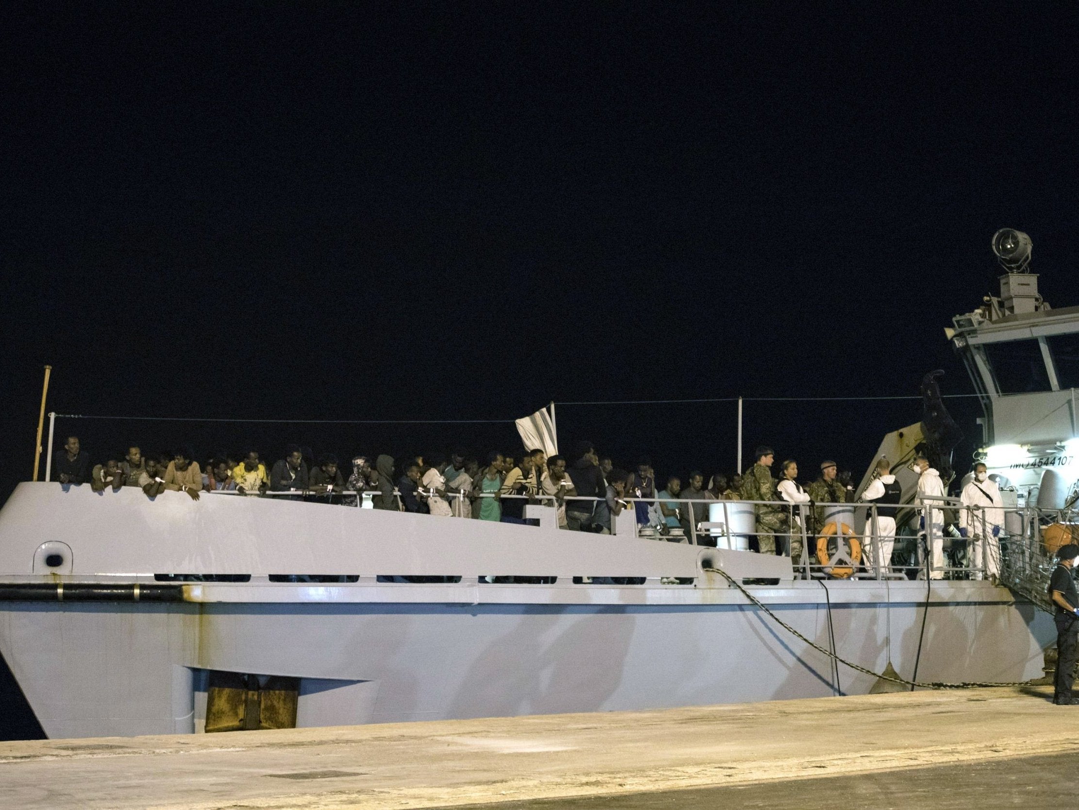Migrants wait to disembark from the Frontex ship, 'Protector', at the port of Pozzallo, Sicily, Italy,