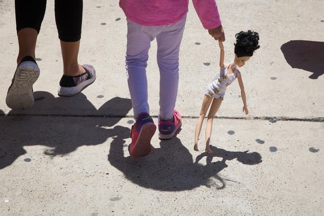 A 4-year-old Honduran girl carries a doll while walking with her immigrant mother, both released from detention