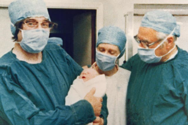 Dr Robert Edwards holding the newborn baby with mother Lesley Brown and obstetrician Dr Patrick Steptoe looking on