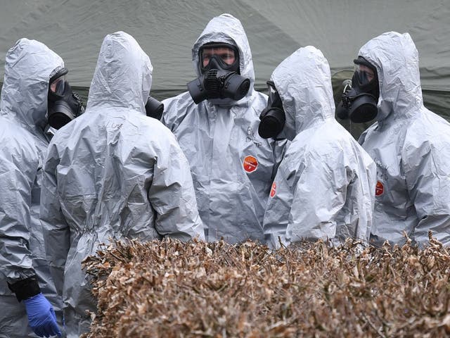 Military officers in protective clothing prepare to remove vehicles from a car park in Salisbury