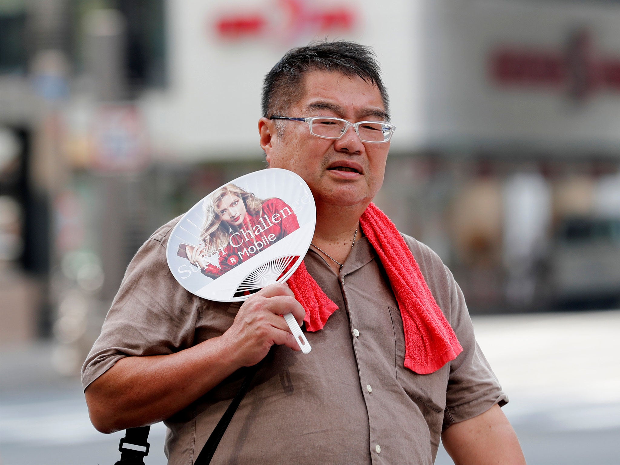 A man uses a fan as he walks on a street in Tokyo