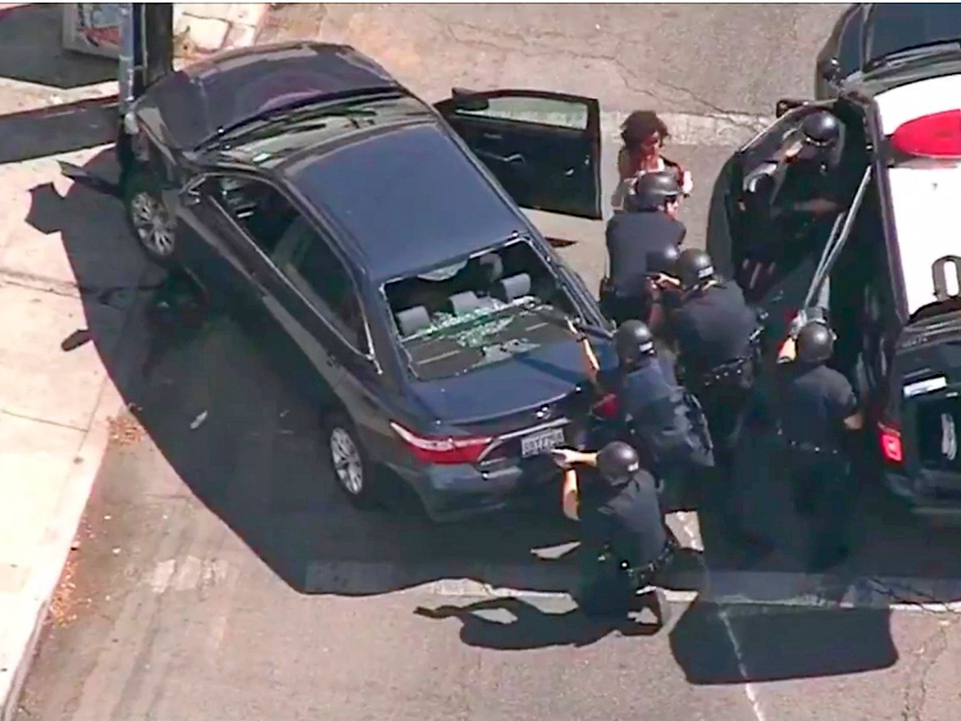 Police officers remove a passenger from the car that crashed outside Trader Joe's supermarket