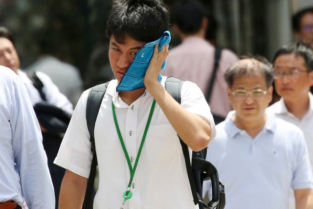 <p>A man wipes the sweat from his face in the scorching heat at a business district in Tokyo</p>