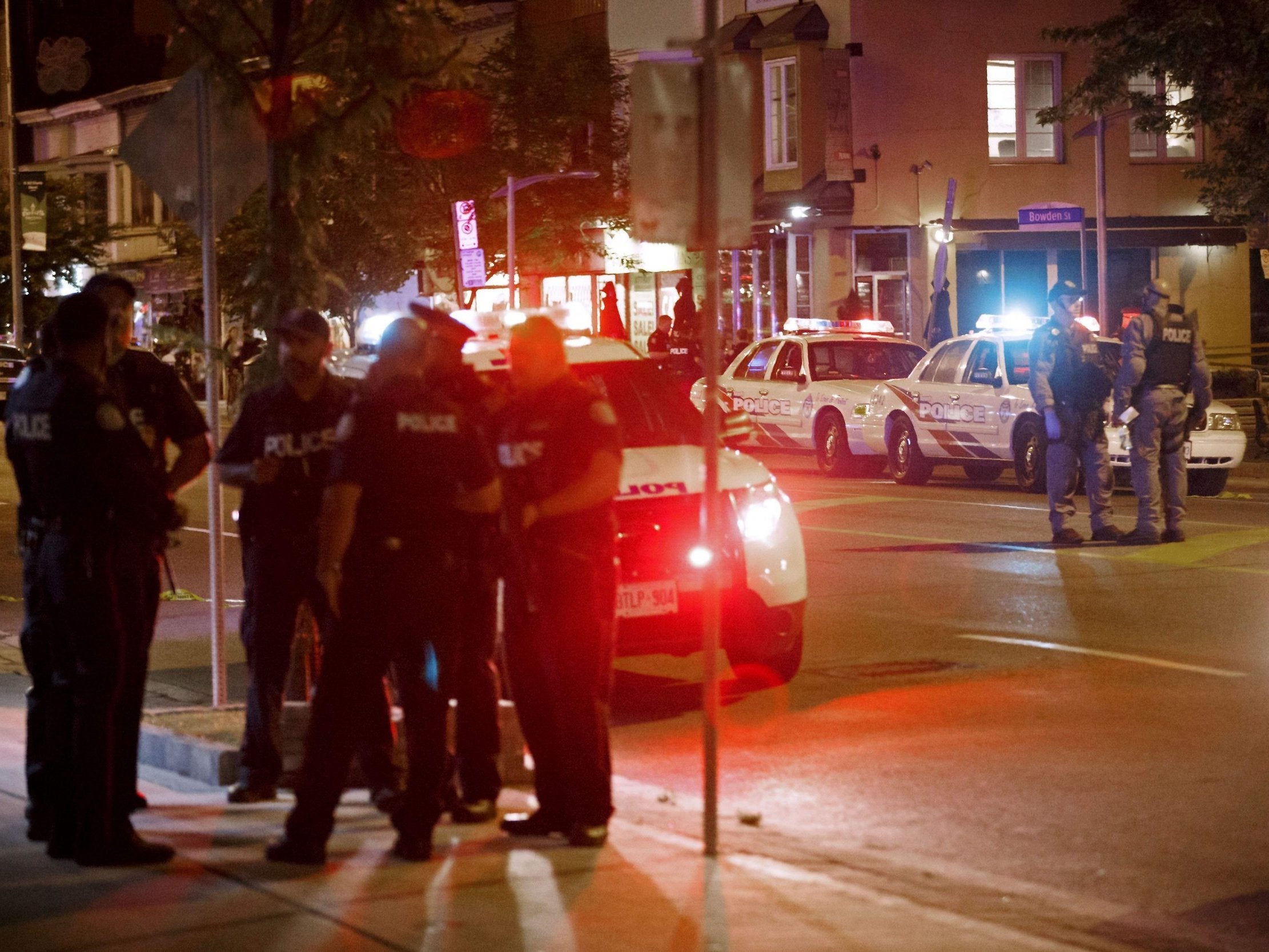 Police officers walk the scene at Danforth Street at the scene of a shooting in Toronto, Ontario