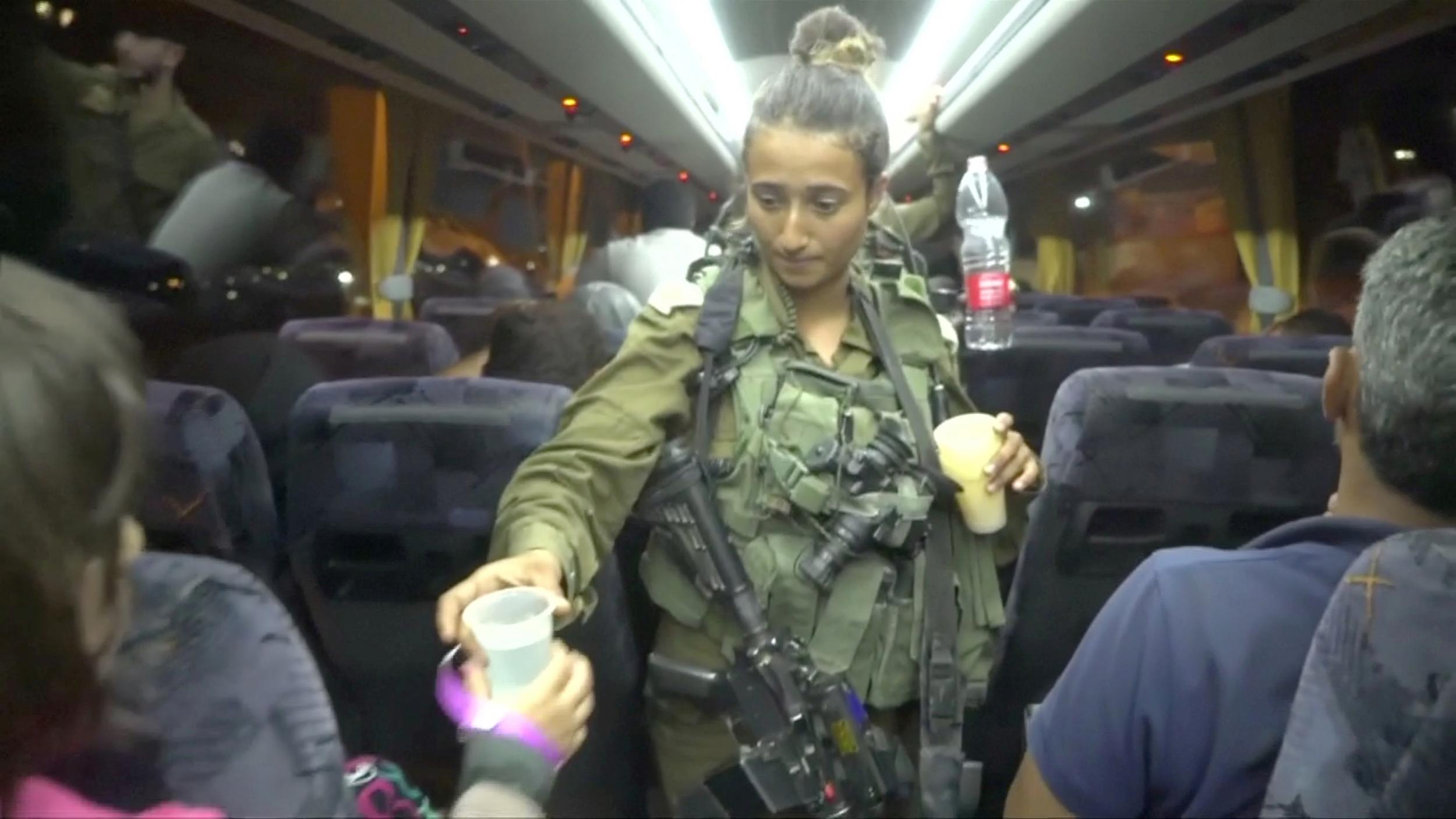 An Israeli soldier hands out water on a bus to Syrians during a rescue operation to extract White Helmets