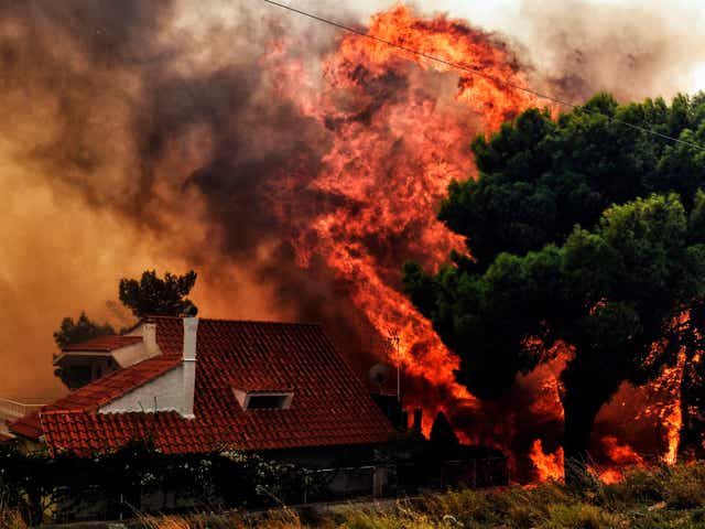 A house is threatened by a huge blaze during a wildfire in Kineta, near Athens