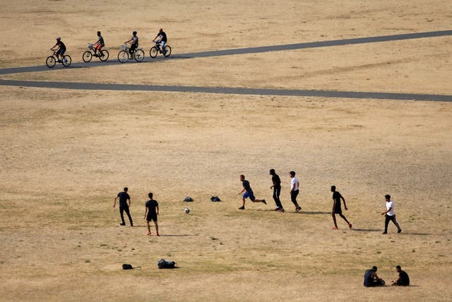 Visitors to Greenwich Park play football on the dry brown grass in London on 23 July