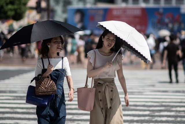 Women shield themselves from the sun with umbrellas in Tokyo on 24 July, 2018, as Japan suffers from a heatwave