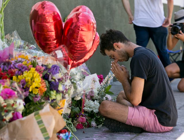 A neighbour of the Trader Joe's prays at a makeshift memorial for Ms Corado