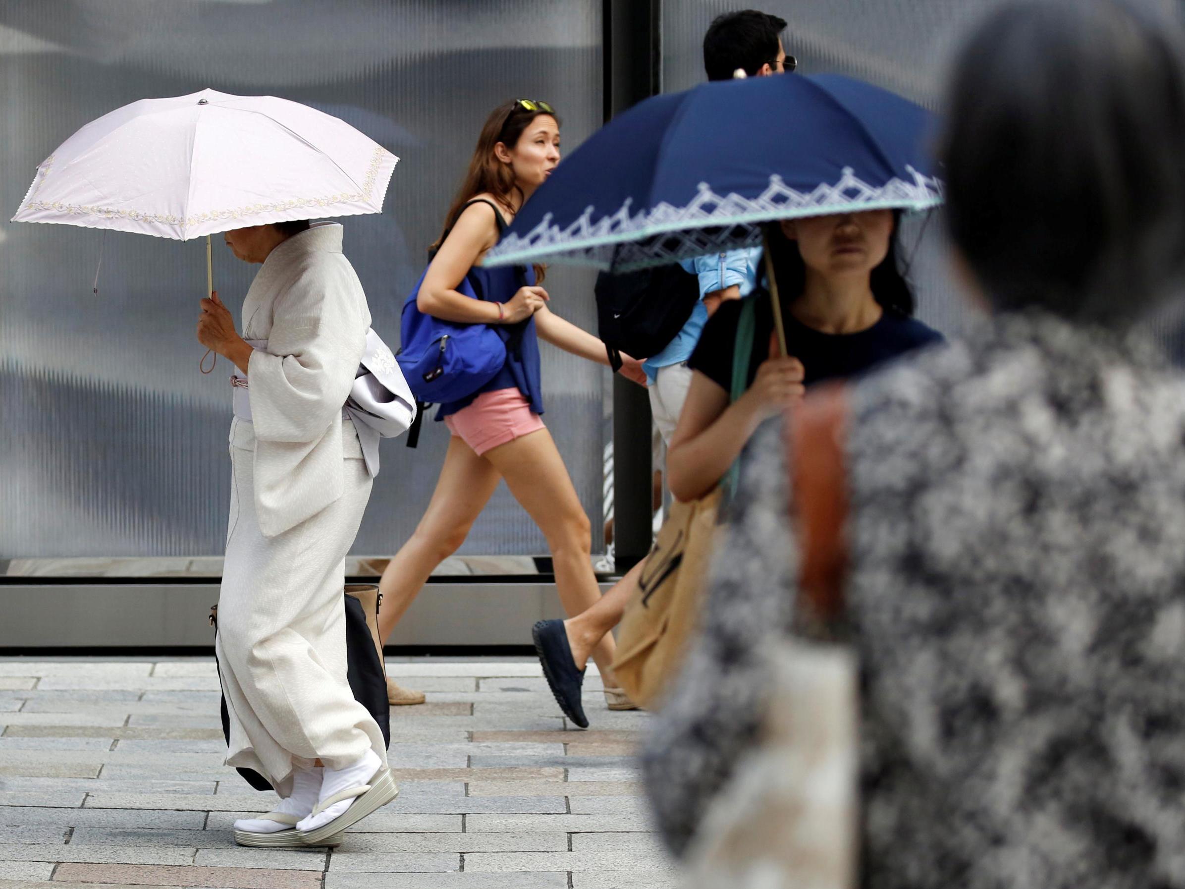 A kimono-clad woman using a sun umbrella walks on a street during a heatwave in Tokyo