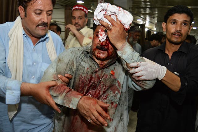 Pakistani volunteers rush an injured person to a hospital following a suicide attack on an election rally in Peshawar on 10 July
