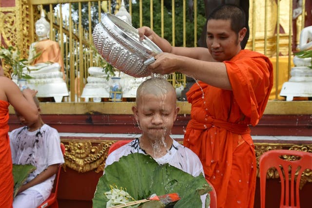A Buddhist monk bathes the shaved head of the rescued Thai boy and a member of 'Wild Boars' football team