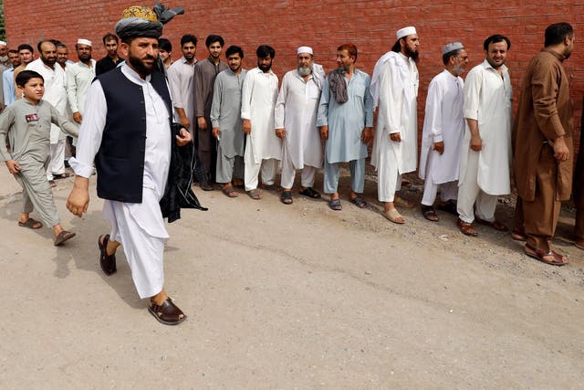 Men stand in line to cast their vote during the general election in Peshawar