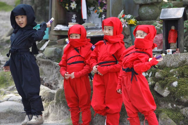 Children dressed as ninjas pose for a souvenir picture during a ninja festival in Iga