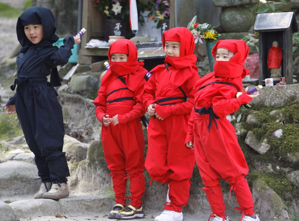 Children dressed as ninjas pose for a souvenir picture during a ninja festival in Iga