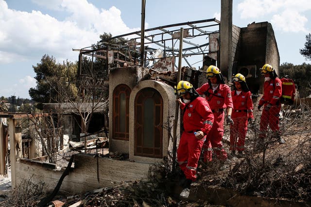 Members of the Greek Red Cross search for missing people at a burned house, following a deadly forest fire in Mati
