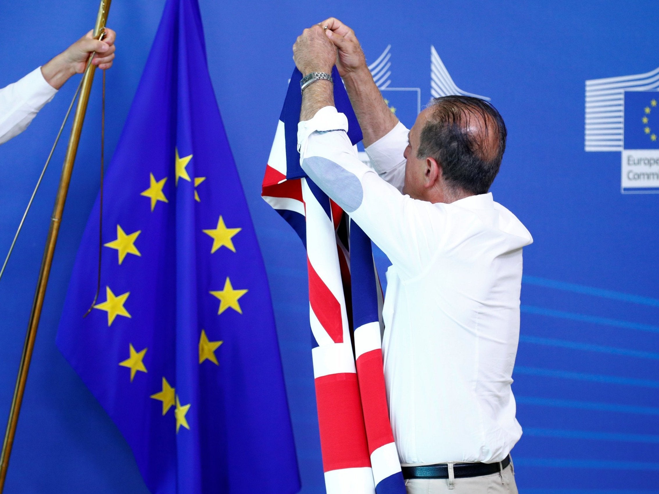 An official carries a Union Jack flag next to the European Union flag, ahead of a meeting between Britain's Secretary of State for Exiting the European Union, Dominic Raab, and European Union's chief Brexit negotiator, Michel Barnier, at the EU Commission headquarters in Brussels