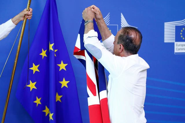 An official carries a Union Jack flag next to the European Union flag, ahead of a meeting between Britain's Secretary of State for Exiting the European Union, Dominic Raab, and European Union's chief Brexit negotiator, Michel Barnier, at the EU Commission headquarters in Brussels