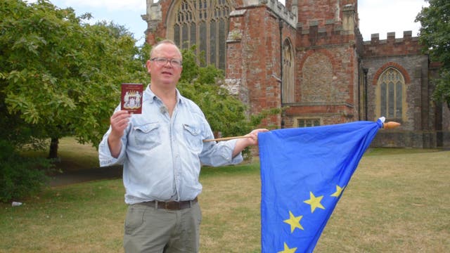 Jonathan Cooper stood with his Totnes passport and an EU flag