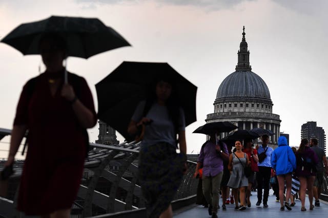 Umbrellas come out on the Millennium Bridge in London as rain brings an end to the hot weather
