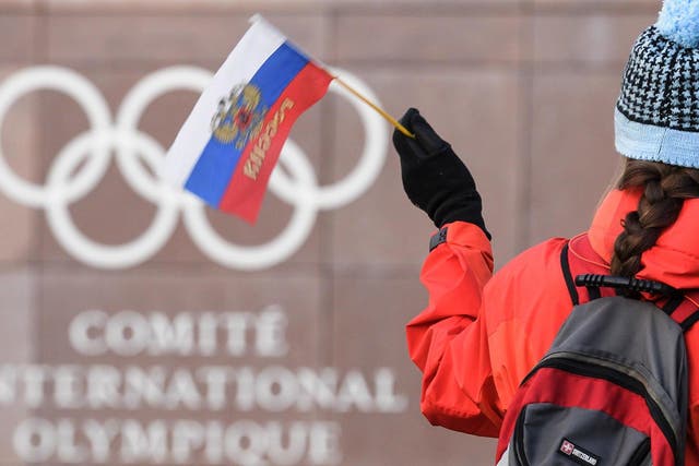 A supporter waves a Russian flag in front of the logo of the International Olympic Committee