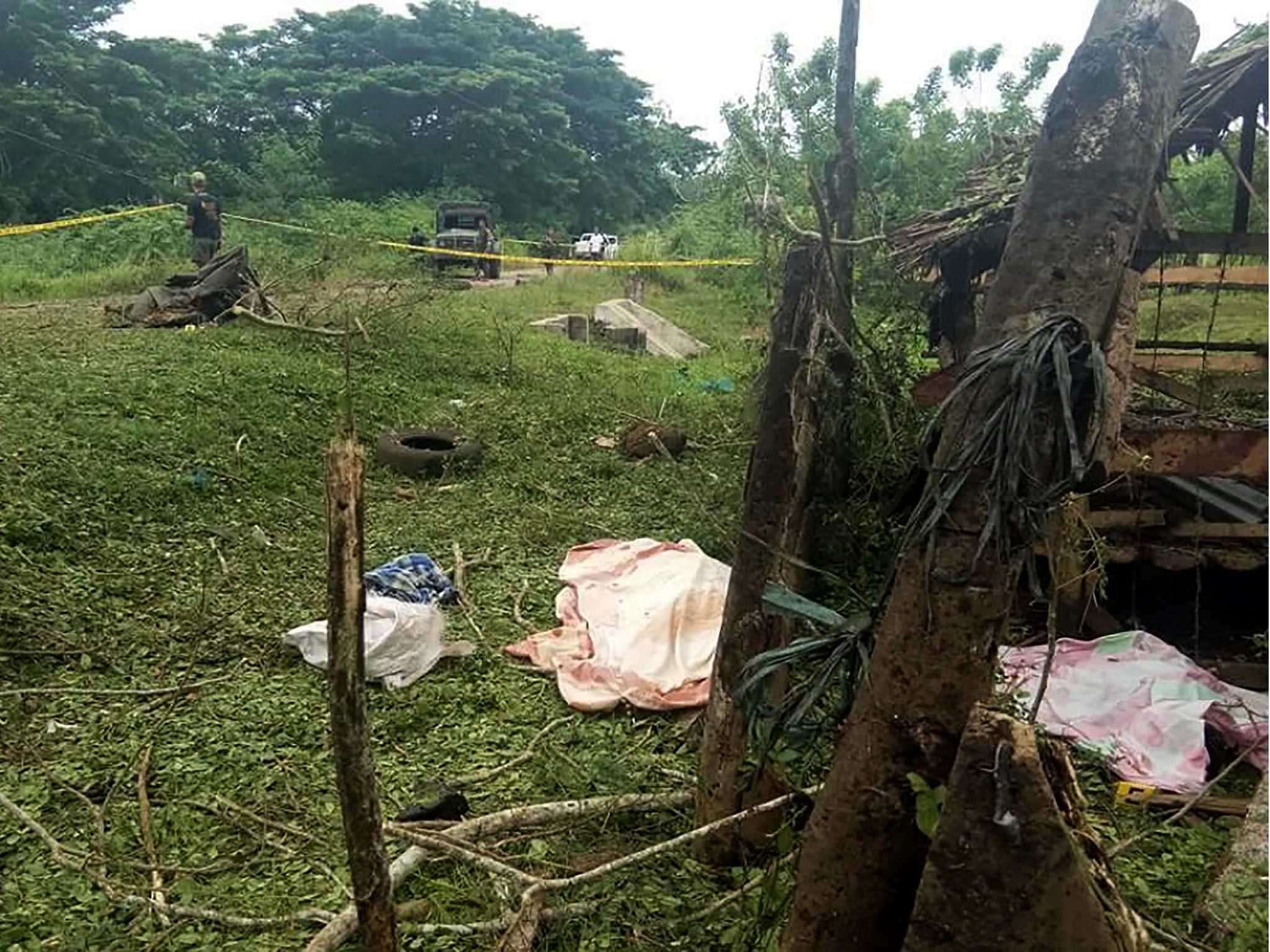 Three unidentified bodies are covered with cloth at the site of the explosion in Lamitan, Basilan province, southern Philippines, on Tuesday