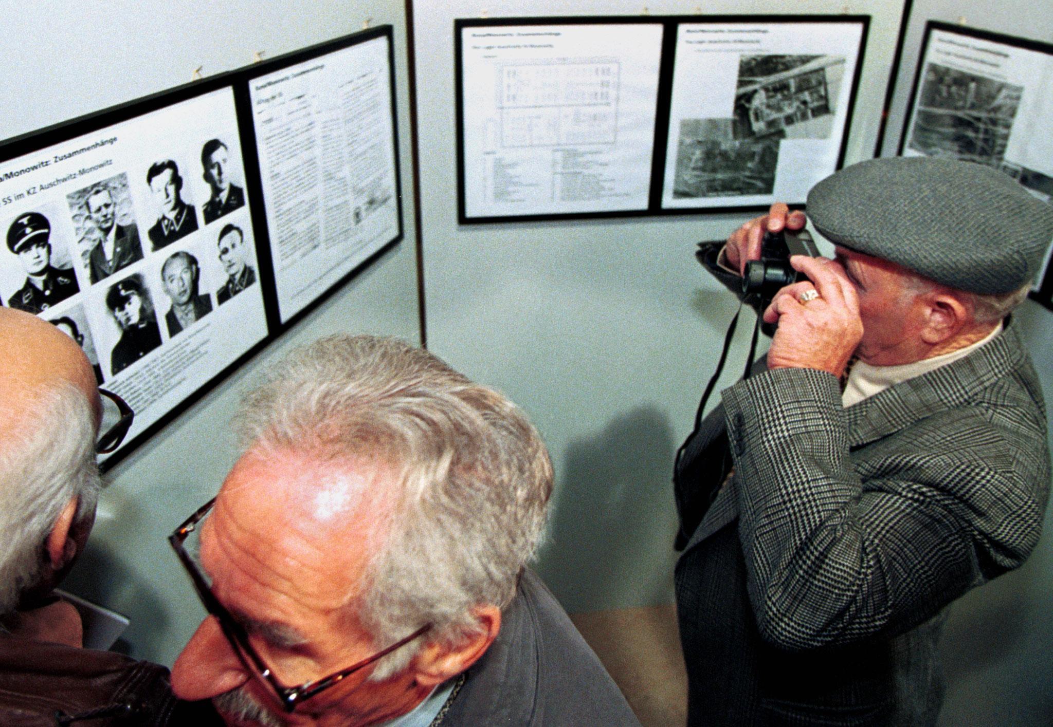 Herman Shine, right, a Holocaust survivor, snaps a picture of the SS guards who held him captive in Auschwitz, during an exhibition in Frankfurt