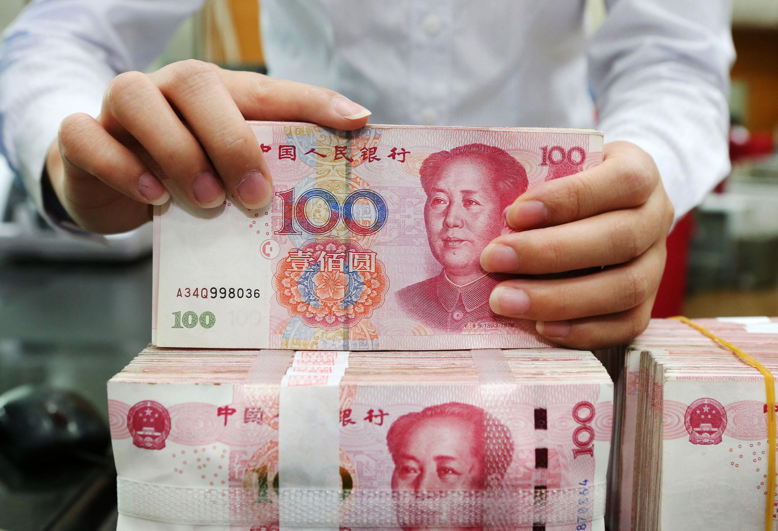 An employee counts 100-yuan notes at a bank in Nantong in China's eastern Jiangsu province